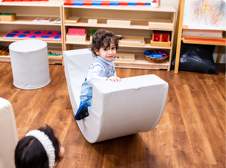 Child playing on a white rocking toy.