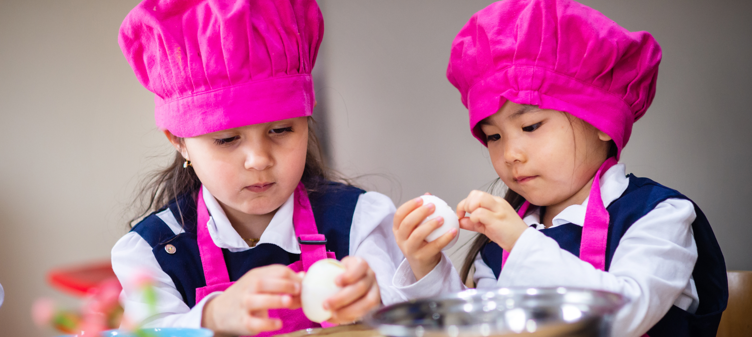 Children cooking with pink chef hats.