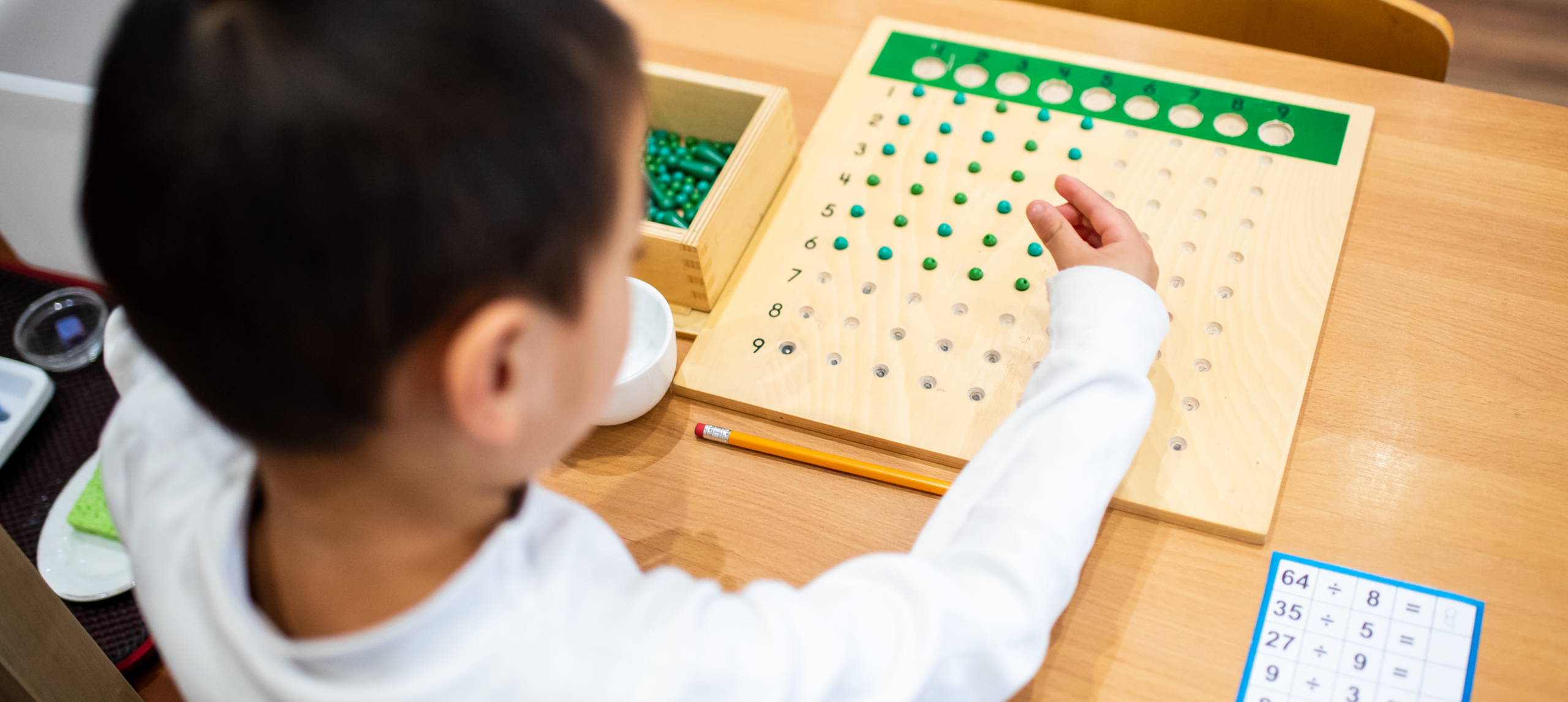 Child learning with math board and beads.