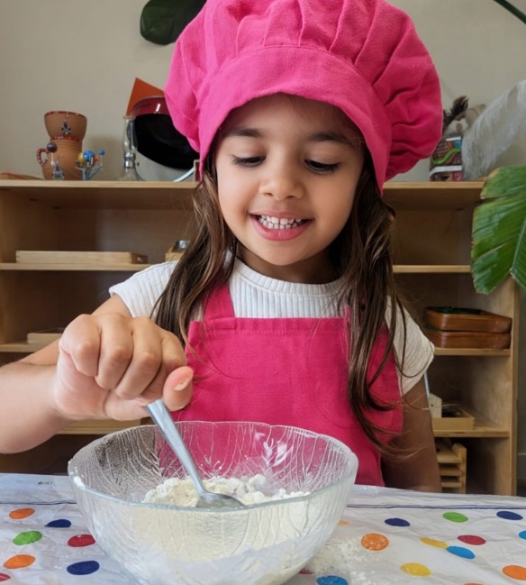 Girl in pink hat mixing ingredients.