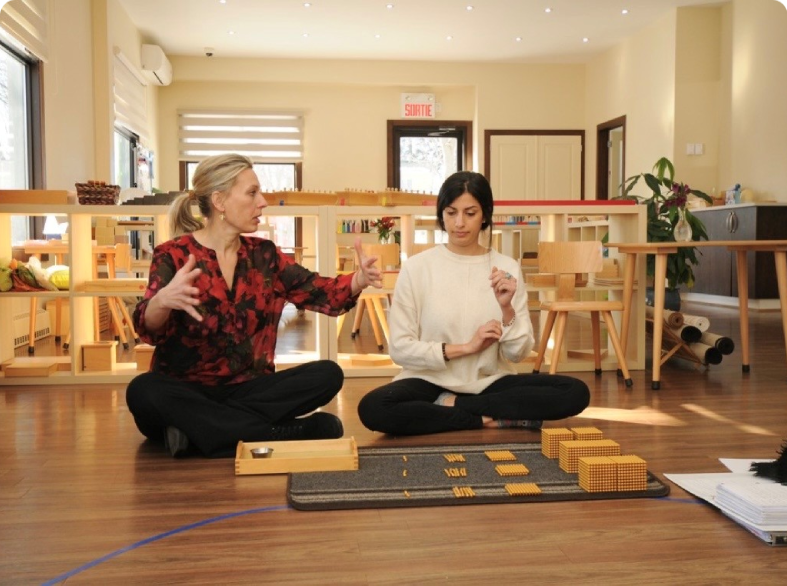 Two women sitting on floor discussing materials.